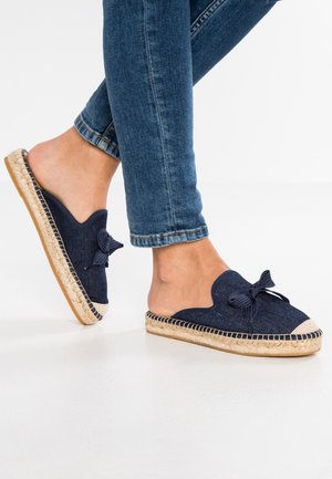 Granatowe espadryle na stopę z falistym wzorem i akcentem w postaci kokardy, z podeszwą z jutowego sznura oraz gumowym spodem. Górna część wykonana z ciemnoniebieskiego materiału tekstylnego.