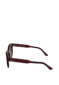 Rdeča prosojna plastična sončna očala z okroglo obliko, s prelivnimi lečami in vzorčastimi stranicami ter zelenim poudarkom.