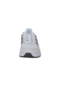 Gray and white athletic shoe with mesh and suede materials, featuring three black stripes, round toe, and white laces. Black rubber sole.