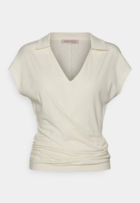 Light cream short-sleeve top with a V-neck and a fold-over collar. Features gathered side details and soft, stretchy fabric.