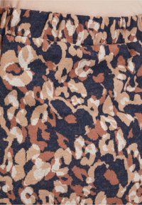 Tissu tricoté avec un motif animal abstrait en bleu marine, marron, beige et blanc, avec une ceinture élastique.