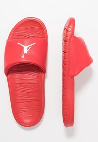 Infradito rossi realizzati in materiale sintetico liscio. Presentano una fascia larga con il logo Jumpman bianco e una soletta testurizzata per una maggiore aderenza.