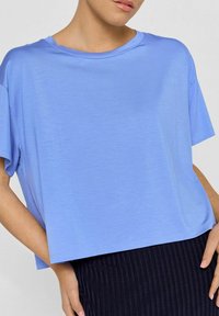 Lys blå, kortærmet t-shirt med løs pasform. Glat tekstur og vid halsudskæring. Kombineret med en mørk, ribbet nederdel.