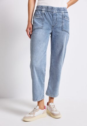 Lichtblauwe denim joggerbroeken met een elastische tailleband, zijzakken en een relaxte pasvorm, gecombineerd met beige en roze sneakers.