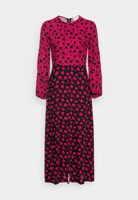 Långärmad klänning med en rosa överdel och en svart kjol med ett mönster av röda hjärtan. Tyget verkar slätt, med en rund halsringning och dragkedja i ryggen.