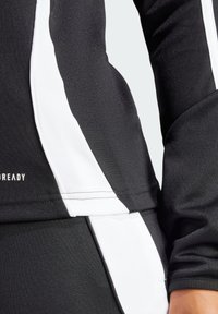 Zwarte sporttop met witte zijpanelen, geweven stof, lange mouwen en een aansluitend ontwerp. Heeft "READY" in kleine letters op de zoom.