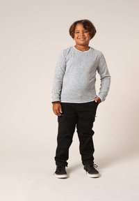 Lichtgrijs langslieverhemd met een ronde hals, gecombineerd met zwarte cargos met zijzakken en zwarte sneakers. Eenvoudig ontwerp.