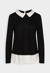 Haut noir à manches longues avec un col blanc, présentant une fermeture éclair discrète au dos et un look superposé avec une base de chemise blanche.