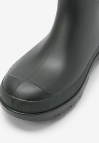 Stivale in gomma nera con punta arrotondata, suola texturizzata e finitura liscia. Presenta una superficie opaca con dettagli delle cuciture visibili.