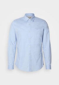 Chemise à manches longues bleu clair en coton, dotée d'un col boutonné, de boutons sur le devant et d'un logo brodé subtilement sur la poitrine.
