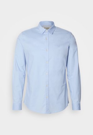 Cămașă albastru deschis cu mâneci lungi, fabricată din bumbac, având un guler cu nasturi, nasturi frontali și un logo subtil brodat pe piept.
