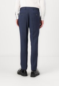 Tailored navy trousers with a textured fabric, straight fit, two back pockets, and a welt design. Paired with black lace-up shoes.