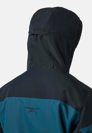 Vista posteriore di una persona che indossa una giacca a cappuccio blu e nera con il logo "Swedemount" e un design di montagna sul retro.
