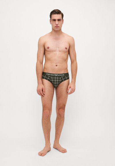 Zeleni karirani kratki donji veš s crnim pojasom na kojem je istaknut logo "EMPORIO ARMANI". Tkanina izgleda glatko; dizajn je uskim krojem.