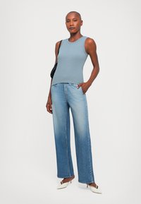 Light blue ribbed tank top, relaxed wide-leg faded denim jeans, and white pointed-toe heels. Minimalist black handbag. Smooth textures.
