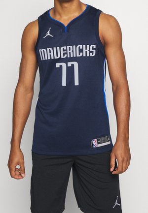 Mand iført mørkeblå Mavericks basketballtrøje med nummer 77 og sorte shorts med synlige Jordan-logoer.