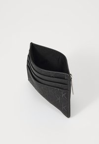 Porte-cartes en cuir noir avec plusieurs emplacements et un compartiment zippé, featuring un motif de logo texturé et un intérieur lisse.
