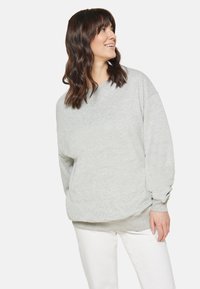 Lichtgrijze oversized sweatshirt, ronde hals, drop shoulders, ribgebreide boorden en zoom. Gecombineerd met witte slim-fit broeken. Zachte stoftextuur.