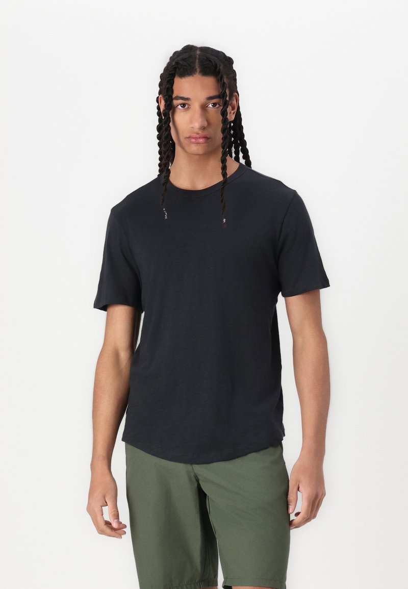 Schwarzes Baumwoll-T-Shirt mit kurzen Ärmeln, rundem Halsausschnitt und lockerer Passform, kombiniert mit olivgrünen Shorts. Keine auffälligen Muster oder Grafiken.