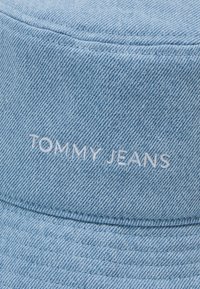 Chapeau seau en denim bleu clair avec logo "TOMMY JEANS" brodé à l'avant, bord rigide avec couture verticale.