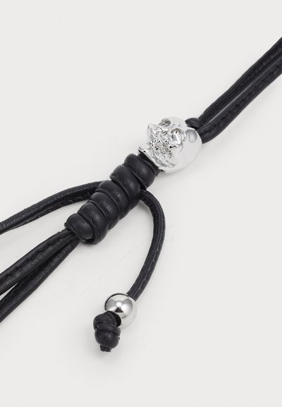 Brățara din piele neagră are un mărgea în formă de cran din argint, cu secțiuni împletite și este securizată cu o nod decorativ și un accent din metal.