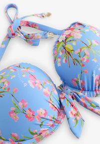 Blaues Bikinioberteil mit rosa Kirschblütenmuster, gepolsterten Cups, verstellbarer Nackenbinde und dekorativem Knoten vorne.