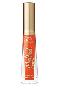 Clear tube of Too Faced Melted Matte orange liquid lipstick with gold cap and gold lettering on white background.