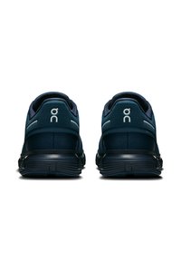 Baskets de sport navy avec panneaux en maille, talon incurvé et logo blanc contrastant. Semelle texturée avec rainures pour une meilleure adhérence.