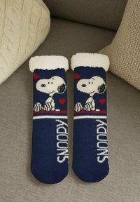 Navy socks featuring a knitted Snoopy design, white faux fur trim, and red accent hearts. Includes "SNOOPY" text in white stripes.