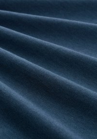 Dunkelblauer Stoff mit strukturierter Oberfläche, der subtile diagonale Linien und Falten aufweist und dadurch Tiefe und ein weiches Erscheinungsbild schafft.