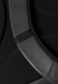Tessuto nero con finitura testurizzata, dotato di una cintura in pelle nera liscia con bordi cuciti e un accento con logo. Design opaco e elegante.