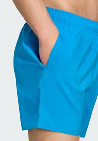 Blaue Schwimmshorts aus leichtem, glattem Material. Mit elastischem Bund und Seitentaschen. Einfaches, einfarbiges Design.