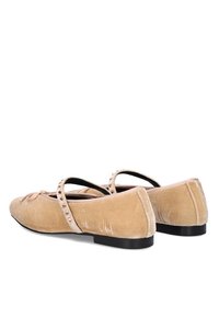 Bailarinas de ante beige con suela plana, tira cruzada y acentos decorativos de tachuelas; punta redondeada y textura suave.