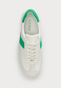 Valged tossud roheliste seemisdetailidega. Omab sileda naha ülaosa, ümarat varvust ja lamedaid paelu. Bränding sisesoolel rohelises tekstis.