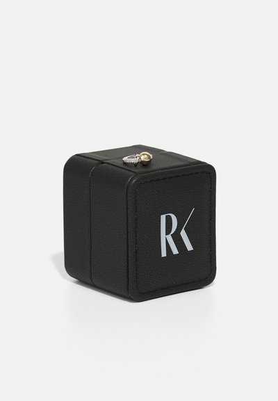 Black leather jewelry box with a textured finish, featuring a silver logo and a gold-accented ring resting on top. Square shape.