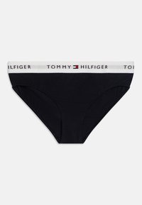 Mutande bikini in cotone nero con una fascia bianca con il logo "TOMMY HILFIGER" e un emblema rosso e blu. Materiale morbido e texture liscia.
