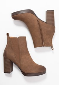 Bottines en suède marron avec un talon épais, fermeture éclair latérale et panneau élastique pour un look ajusté. Présente un talon texturé et un design à bout rond.