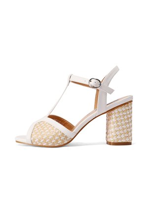 Sandalo bianco con tacco, caratterizzato da un accento in fibra naturale intrecciata e testurizzata nella parte anteriore. Presenta una cinturino alla caviglia con una fibbia argentata e un tacco spesso.