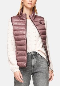 Chaleco exterior acolchado sin mangas en un color malva apagado, con cuello alto, cierre de cremallera y detalles de bolsillo lateral con cierre de presión.