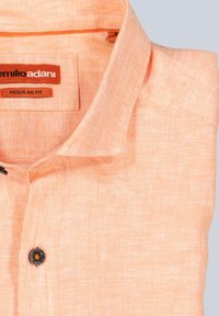 Helles orange Kurzarmhemd aus einem strukturierten Stoff. Verfügt über einen Kragen und einen einzelnen dunklen Knopf vorne. Reguläre Passform.