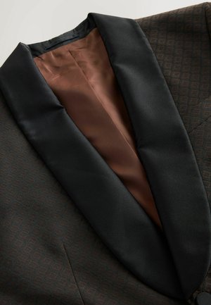 Brown patterned blazer with a black satin shawl collar and brown lining. Features a subtle geometric design across the fabric.