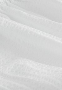 Tissu blanc avec un motif texturé, présentant de doux plis et une apparence légère et aérée. La surface est lisse et légèrement transparente.