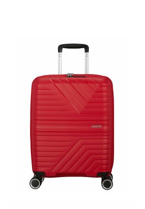Valise American Tourister rigide rouge avec quatre roues pivotantes et poignée télescopique noire déployée.