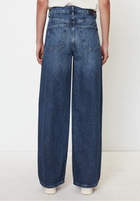 Wide-leg blue denim jeans with a high waist, featuring back pockets and a raw hem. The texture appears slightly faded, with sturdy stitching.
