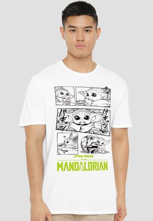 Mann trägt weißes T-Shirt mit schwarz-weißen Comic-Panels von Baby Yoda und grünem "Star Wars The Mandalorian" Text darunter.