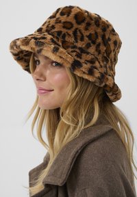 Kapa u obliku kante s leopard uzorkom, napravljena od plišanog materijala u nijansama smeđe boje, s mekanom teksturom i širokim obodom. Oslikava se detaljem s uvijanim rubom.