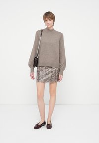 Barna kötött pulóver magas nyakú, ballon ujjakkal; mintás kígyóbőr mini szoknya; fényes bordó lapos cipők; kicsi keresztpántos táska.