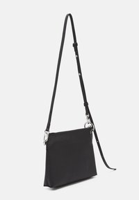 Czarna skórzana torebka na ramię z teksturowaną powierzchnią, zamknięciem na zamek błyskawiczny i regulowanym paskiem. Posiada metalowe elementy oraz smukły prostokątny kształt.