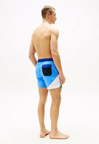 Shorts de bain colorés avec des sections bleues, blanches et vertes, dotés d'une poche noire et d'une taille élastique. Matériau léger et à séchage rapide.