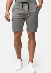 Shorts cargo gris en denim, avec deux poches latérales, taille élastique avec cordon de serrage, et coupe décontractée. Assortis à des baskets blanches.